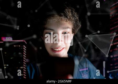 Ein junger attraktiver Mann nutzt in einem dunklen Raum spät in der Nacht das Handy Stockfoto