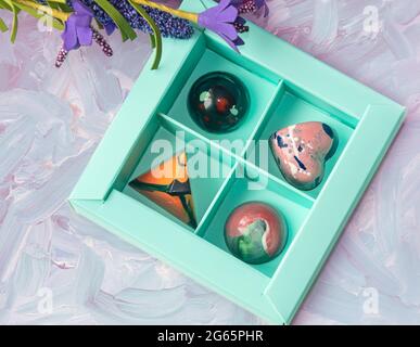 Bonbons aus gehärteter Schokolade mit glänzend lackiertem Körper in einer Schachtel mit Blur-Elementen. Blick von oben. Stock-Fotografie. Stockfoto