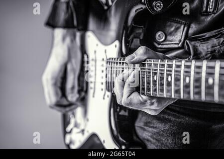 E-Gitarre. Nahaufnahme der Hand, die Gitarre spielt. Musiker spielt Gitarre, Live-Musik. Schwarz und Weiß Stockfoto