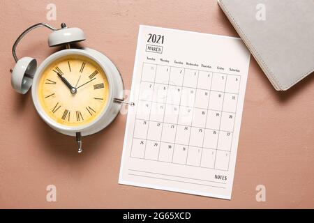 Papierkalender und Wecker auf farbigem Hintergrund drehen Stockfoto