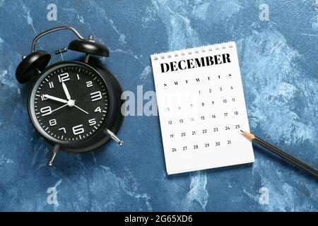 Papierkalender, Bleistift und Wecker auf farbigem Hintergrund drehen Stockfoto