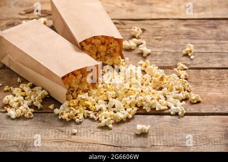 Papiertüten mit leckerem Popcorn auf Holzhintergrund Stockfoto