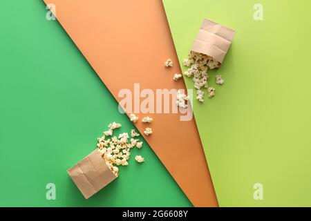 Papiertüten mit leckerem Popcorn auf farbigem Hintergrund Stockfoto