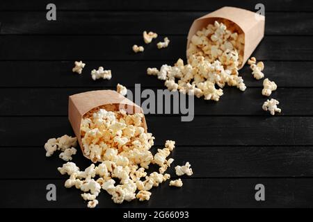 Papiertüten mit leckerem Popcorn auf dunklem Holzhintergrund Stockfoto