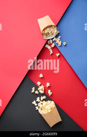 Papiertüten mit leckerem Popcorn auf farbigem Hintergrund Stockfoto