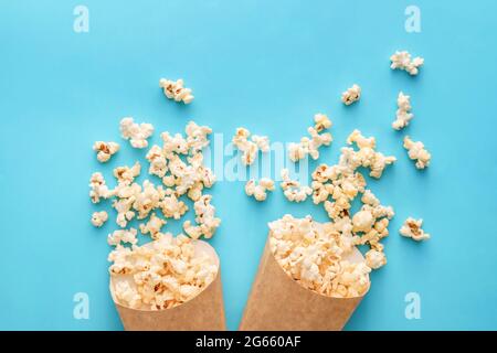 Papiertüten mit leckerem Popcorn auf farbigem Hintergrund Stockfoto