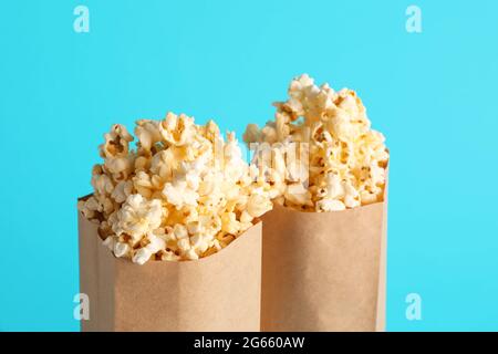 Papiertüten mit leckerem Popcorn auf farbigem Hintergrund, Nahaufnahme Stockfoto