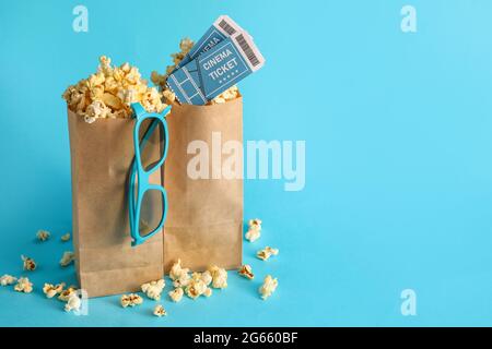 Papiertüten mit leckerem Popcorn, Kinokarten und 3D-Brillen auf farbigem Hintergrund Stockfoto