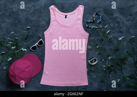 Tanktop aus rosa Baumwolle auf dunklem Hintergrund. Leere einfarbige T-Shirt-Vorlage für kreatives Design. Weibliche Sommer Sonnenbrillen Kleidung Mode ärmellos Stockfoto