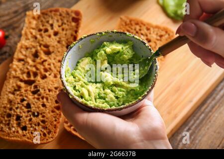 Frau macht Avocado-Püree für leckere Sandwiches auf Holztisch, Nahaufnahme Stockfoto