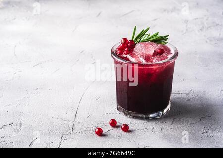 Frischer eisgekühlter Fruchtcocktail im Glas, erfrischender Sommerdrink mit roten Johannisbeeren und Rosmarinblättern auf Steinbeton-Hintergrund, Blick auf den Winkel Copy Spa Stockfoto