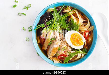 Miso-Suppe. Japanische Ramen-Suppe mit Huhn, Ei, Nori und Nipposinica auf hellem Hintergrund. Draufsicht, flach liegend Stockfoto