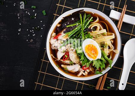 Miso-Suppe. Japanische Ramen-Suppe mit Huhn, Ei, Nori und Nipposinica auf dunklem Grund. Draufsicht, flach liegend Stockfoto