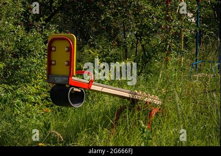 Eine überwuchert und verlassene Schaukel mitten im Wald. Viel Gras. Die Natur übernimmt. Seltsame Gefühle. Stockfoto