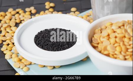 Sojamilch gemischt mit schwarzem Sesam in klarem Glas auf schwarzer Plattenmatte. Schwarzer Sesamsamen und Sojabohnen in einer Tasse. Schwarze Sojabohnenmilch mit Sesam. Er Stockfoto