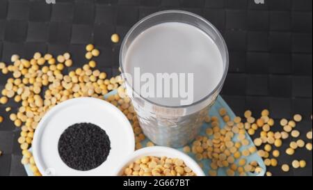 Sojamilch gemischt mit schwarzem Sesam in klarem Glas auf schwarzer Plattenmatte. Schwarzer Sesamsamen und Sojabohnen in einer Tasse. Schwarze Sojabohnenmilch mit Sesam. Er Stockfoto