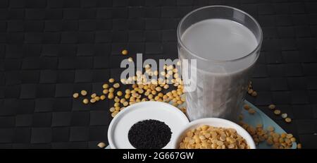 Sojamilch gemischt mit schwarzem Sesam in klarem Glas auf schwarzer Plattenmatte. Schwarzer Sesamsamen und Sojabohnen in einer Tasse. Schwarze Sojabohnenmilch mit Sesam. Er Stockfoto