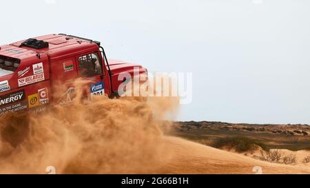 Die Rivalität zwischen Kamaz und Maz bei der Rallye. Der Sporttruck KAMAZ übersteht den schwierigen Teil der Strecke während des Rallye-Angriffs im Sand. DAS GOLD Stockfoto