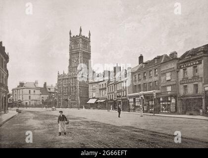 Ein Blick aus dem späten 19. Jahrhundert von der Dyer Street auf die Cirencester-Kirche St. Johannes der Täufer, bekannt für seine rechtwinklige gotische Veranda, die die architektonischen Stile seit dem 12. Jahrhundert widerspiegelt. Die Marktstadt in Gloucestershire, England, liegt am Fluss Churn, einem Nebenfluss der Themse, und ist die größte Stadt in den Cotswolds. Stockfoto