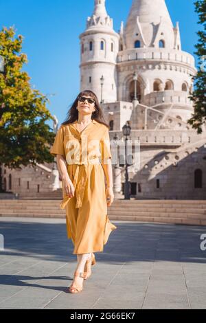 Alleinreisende Frau Porträt. Stilvolle modische glücklich mittleren Alters Frau Reisende tragen gelbe Kleid Spaziergänge in Fisherman Bastion in Budapest Ungarn. Stockfoto