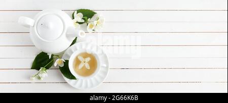 Jasminblüten und Teekannen auf weißem Holzhintergrund. Kräutertee aus Jasminblüte. Flach liegend. Stockfoto