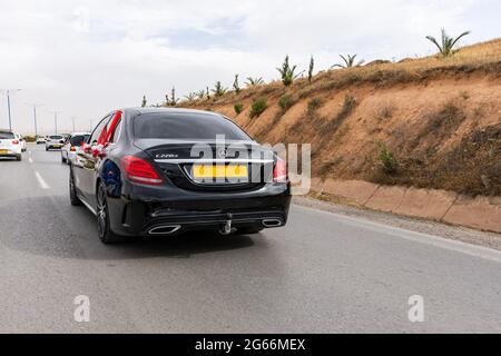 Rückansicht eines schwarzen Hochzeitswagens auf der Straße mit rotem Organza-Stoff und Schleife. Stockfoto