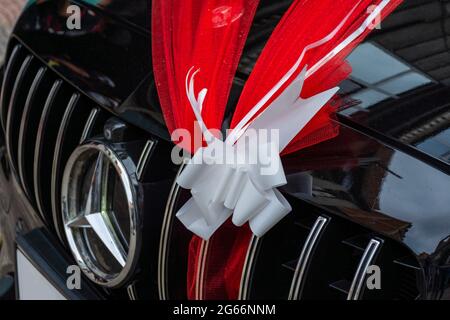 Schwarzes Hochzeitsauto, roter Organza-Stoff, Schleife, Vorderwagen. Stockfoto