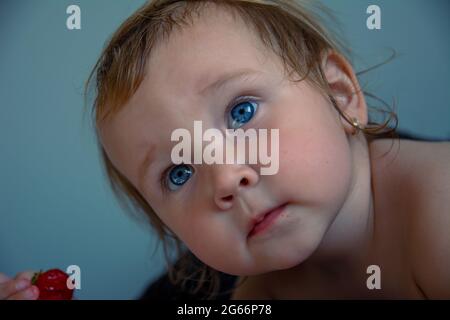 Ein schönes kleines kaukasisches Mädchen schaut ernsthaft mit großen Augen in den Rahmen. Porträt eines Kindes. Stockfoto