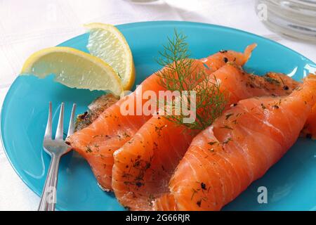 Scheiben ausgehärteter Gravlax auf einer blauen Schale. Stockfoto