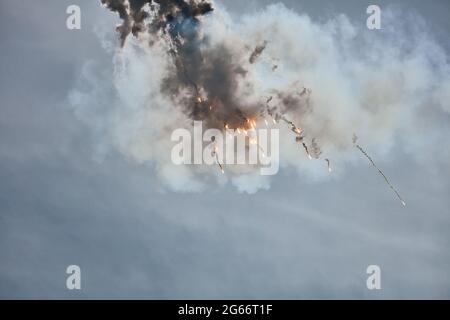 Flugzeugjäger fliegt und schießt Heißluftgewehre in den blauen Himmel. Der Kämpfer schießt während des Manövers Wärmestauben ab. Ein Kämpfer während einer Demonstration Stockfoto