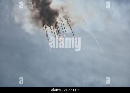 Flugzeugjäger fliegt und schießt Heißluftgewehre in den blauen Himmel. Der Kämpfer schießt während des Manövers Wärmestauben ab. Ein Kämpfer während einer Demonstration Stockfoto