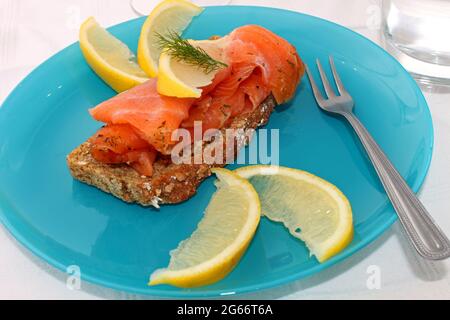 Schichten von Lachs auf braunem Brot mit Zitronenscheiben. Stockfoto