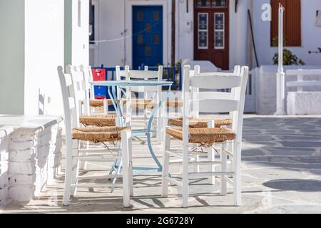 Griechische Insel, Café-Bar im Freien. Typische Cafeteria mit Tisch und Stühlen. Leere Plätze, sonniger Tag in Kythnos Chora Dorf gepflasterte Gasse. Sommer VA Stockfoto