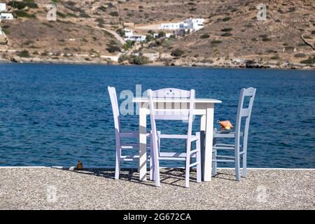 Griechische Insel im Freien Taverne. Typische Taverna am Meer mit Tisch und Stühlen. Leere Plätze, sonniger Tag im iOS Port Fish und Sea Food Restaurant. Sommerurlaub Stockfoto