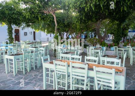 Griechische Insel im Freien Tavernen Tische. Typisches Taverna-Restaurant mit Holztischen und -Stühlen. Leere Plätze am Dorfplatz von Folegandros Chora. Sommerurlaub Stockfoto