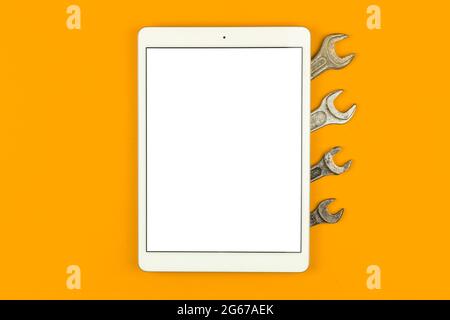 Bauservice-Mockup-Bildschirm, Tablet auf dem Tisch mit professionellen Werkzeugen, orangefarbener Hintergrund, Draufsicht, flacher Lay- und Kopierraum Stockfoto