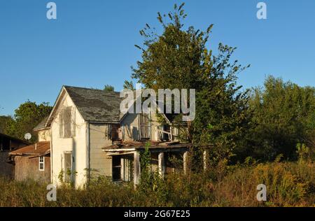 Ein verlassenes Haus steht auf einem überwuchernen ländlichen Grundstück entlang der Route 66 in der Nähe von Warwick, Oklahoma. Stockfoto