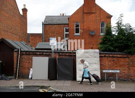 Loughborough, Leicestershire, Großbritannien. Juli 2021. Eine ältere Frau kommt an Müll vorbei, den Universitätsstudenten auf den Straßen hinterlassen haben, um ihre Häuser zu räumen Stockfoto