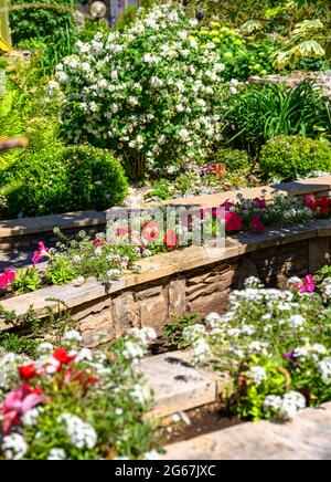 Landschaftsgestaltung von schönen Hausgarten, Landschaftsgestaltung mit Stützmauern und Blumenbeete in Wohnhaus Hinterhof. Wunderschöne Landschaft im Freien Stockfoto