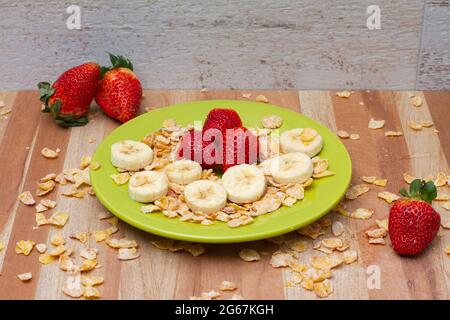 Erdbeere, Banane und Getreide auf einer grünen Schale Stockfoto