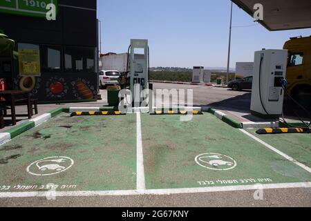 Zwei Ladestationen für Elektroautos mit ausgewiesenen grünen Parkplätzen, die auf Hebräisch für Elektroautos gekennzeichnet sind, nur an einer normalen Gas- oder Tankstelle. Stockfoto
