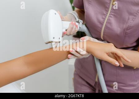 Laser Haarentfernung in Aktion. Kosmetikerin, die eine Laserepilation auf der Hand einer Frau mit einem antikalen Gel macht. Nahaufnahme im Spa-Salon Stockfoto