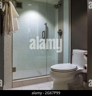 Interieur des modernen Badezimmer mit Glastür geflieste Dusche und WC mit Handtüchern Stockfoto