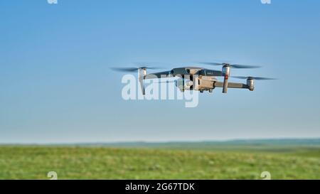 New Raymer, CO, USA - 8. Juni 2021: Funkgesteuerte Quadcopter-Drohne DJI Mavic 2 Pro fliegt über grüne Prärie. Stockfoto