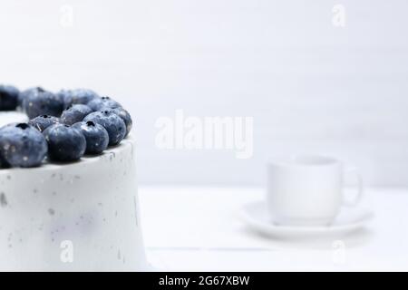 Auf dem Tisch steht weißer Kuchen, der auf Heidelbeeren dekoriert ist Stockfoto