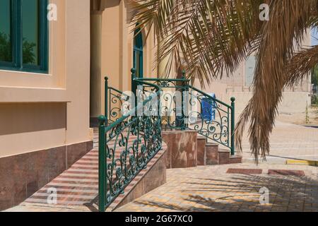 Vorne elegante Veranda mit kunstvoll geschmiedeten floralen Design Geländer mit Treppe und sanfte Rampe für einfachen Zugang von Kinderwagen und Rollstühle Benutzer. Stockfoto