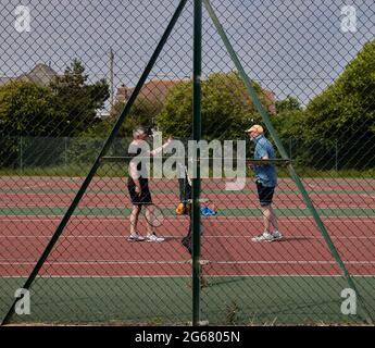 Zwei Männer bereiten sich im Sommer 2021 auf ein Tennisspiel vor, das im vereinigten königreich ausreißt. Stockfoto