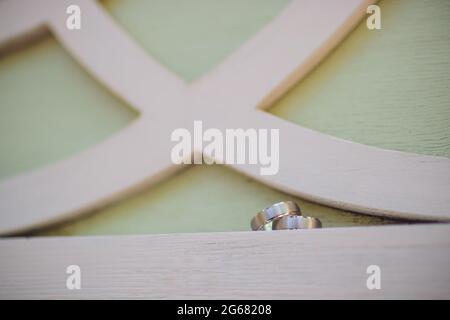 Paar Hochzeitsringe aus Weißgold mit Diamanten im Damenring. Silbernes Eheringe-Band mit Edelsteinen auf minimalistischem grauen Hintergrund mit Schattendagen Stockfoto