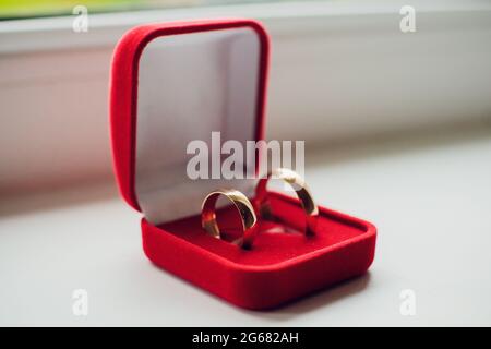 Paar Hochzeitsringe aus Weißgold mit Diamanten im Damenring. Silbernes Eheringe-Band mit Edelsteinen auf minimalistischem grauen Hintergrund mit Schattendagen Stockfoto