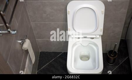 Weiße Toilettenschüssel im Innenraum, moderne Toilette. Desinfektion der Toilette, Reinigung der Toilette, Abwaschen von Schmutz von der Toilette, Abspülen Stockfoto